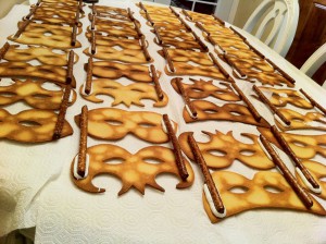 Pretzel rods added with royal icing to the decorated mask cookies 