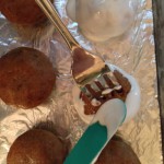 Carefully setting the covered cake ball on the tray and removing the fork