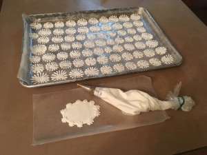 Piping royal icing daisies and birthday message plaque